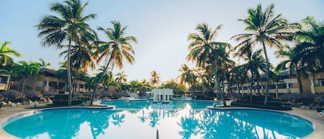 Una piscina al aire libre, sombrillas, sillones reclinables de piscina