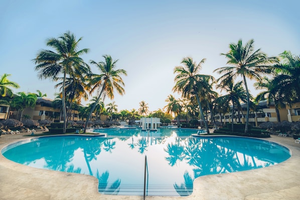 Una piscina al aire libre, sombrillas, sillones reclinables de piscina