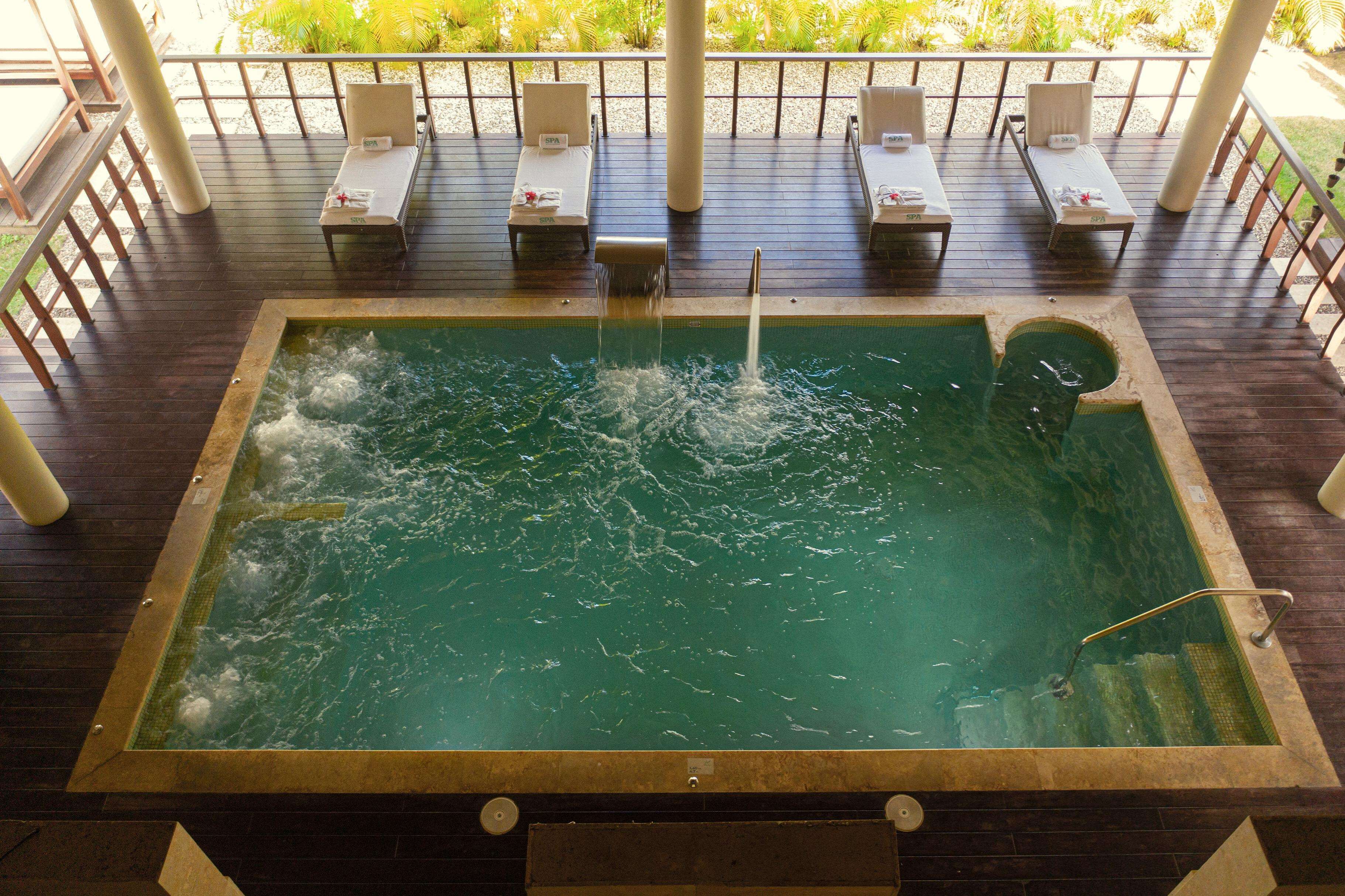 Ein Whirlpool mit Wasserdüsen, umgeben von Liegestühlen und einer Holzterrasse.