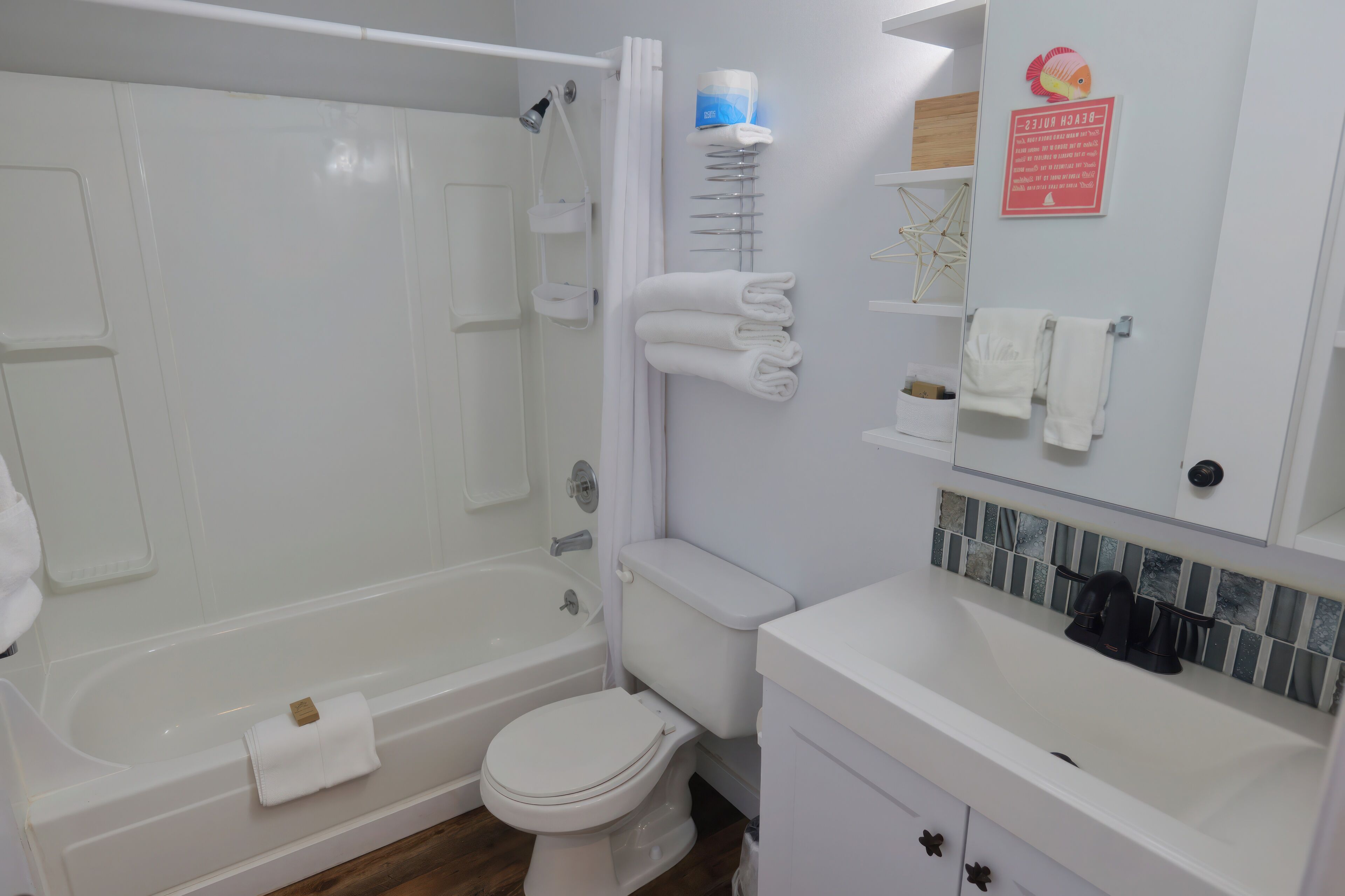 Un bagno con vasca, WC e lavandino. Asciugamani e articoli da toilette a parete.