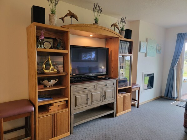 Una sala de estar con un mueble de madera para entretenimiento, un televisor de pantalla plana y un pequeño armario.