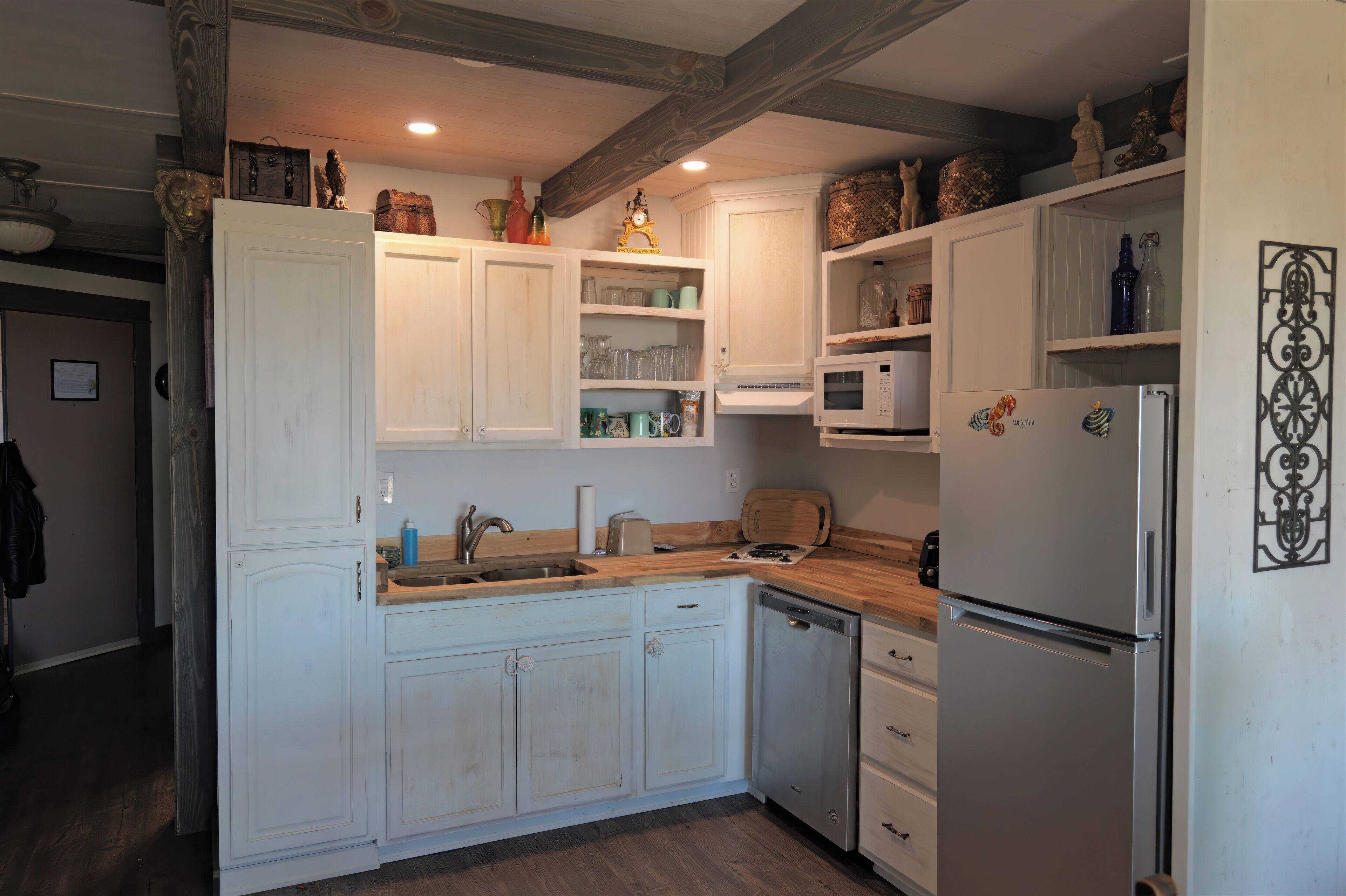 Una cocina con armarios blancos, un fregadero, un microondas y un refrigerador.