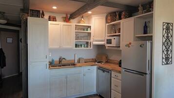 Una cocina con armarios blancos, un fregadero, un microondas y un refrigerador.