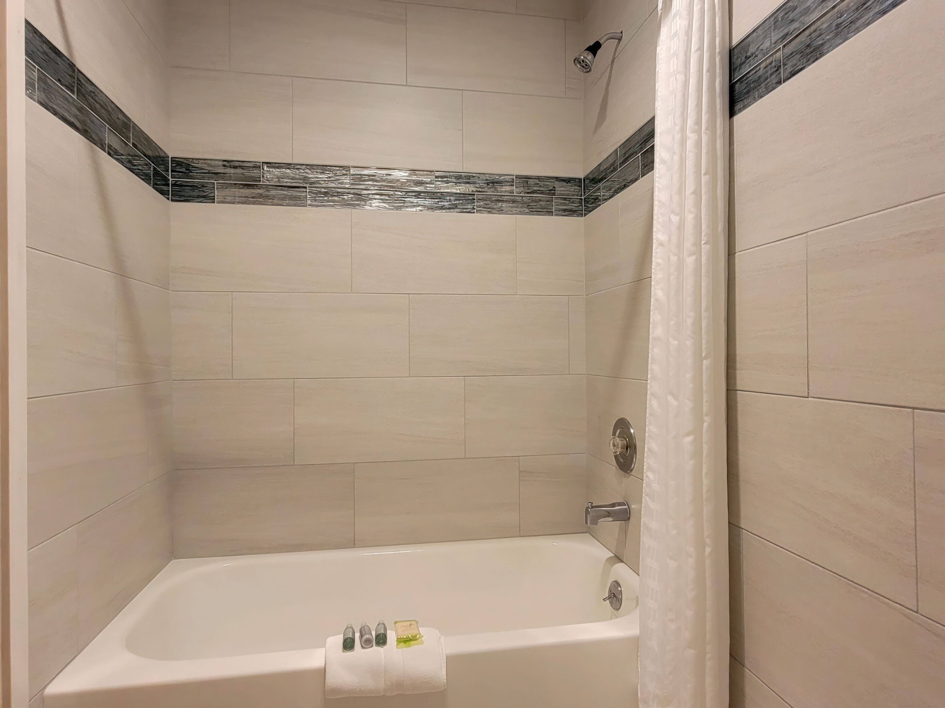 A bathroom with a bathtub, a showerhead, and a curtain.