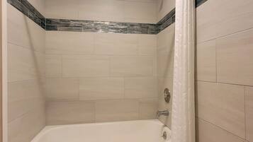 A bathroom with a bathtub, a showerhead, and a curtain.
