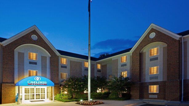 Un hôtel reconnaissable à son grand drapeau américain, à son auvent bleu portant l’inscription « Candlewood Suites » et à sa façade en briques.