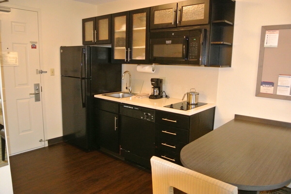 A compact kitchen with a refrigerator, microwave, sink, and coffee maker.