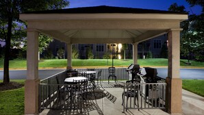 Une terrasse extérieure dotée d’un espace salon couvert, de tables, de chaises et d’un barbecue.