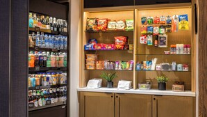 Een automaat gevuld met drankjes en snacks, en een plank met verschillende verpakte producten.