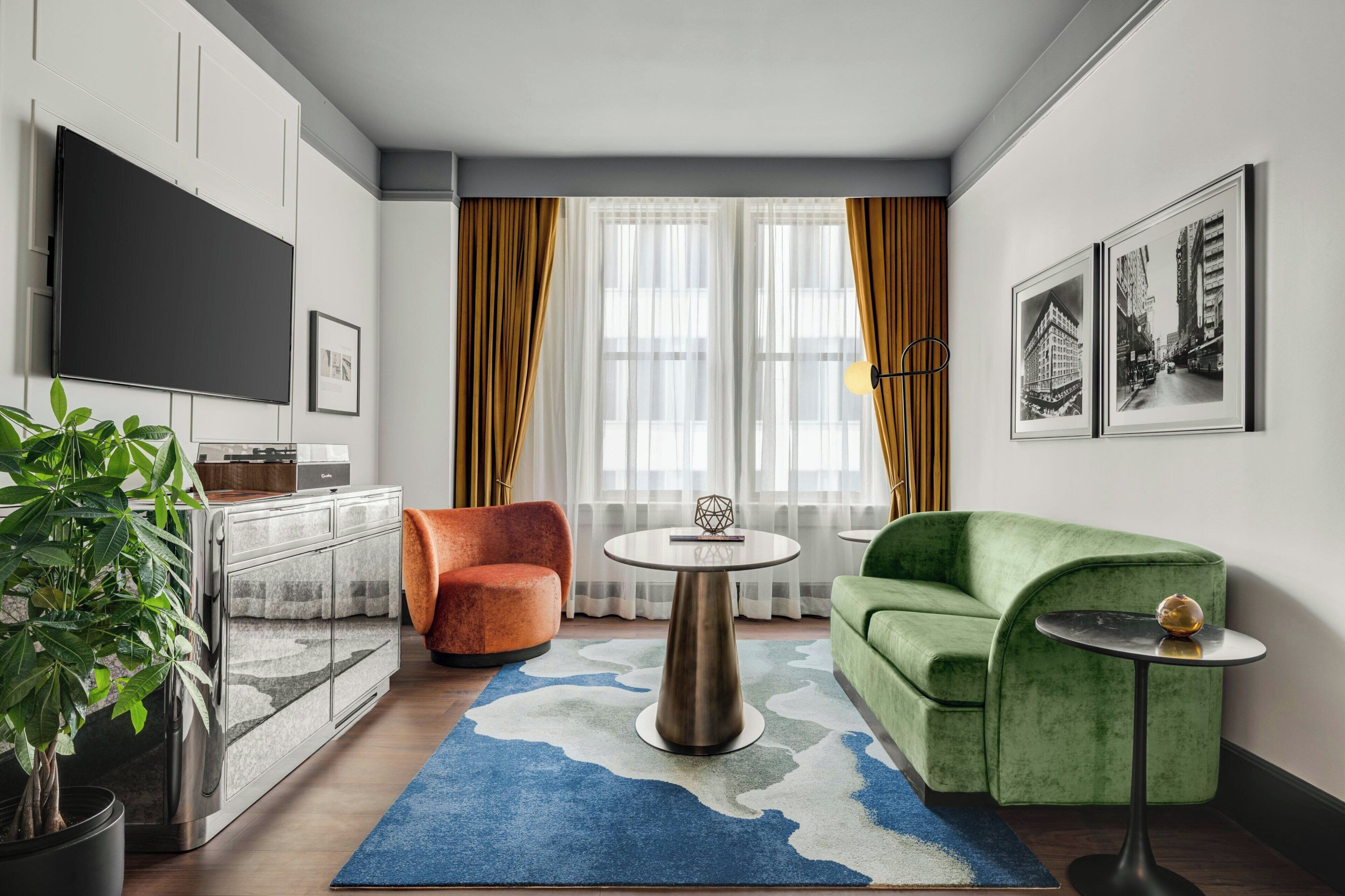 Ein modernes Wohnzimmer mit Sofa, Sessel, Fernseher und Kunstwerk an der Wand.