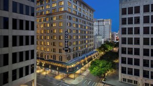 Ett hotell med flera våningar, utformat i en klassisk arkitektonisk stil, med en framträdande entré och en väl upplyst fasad.
