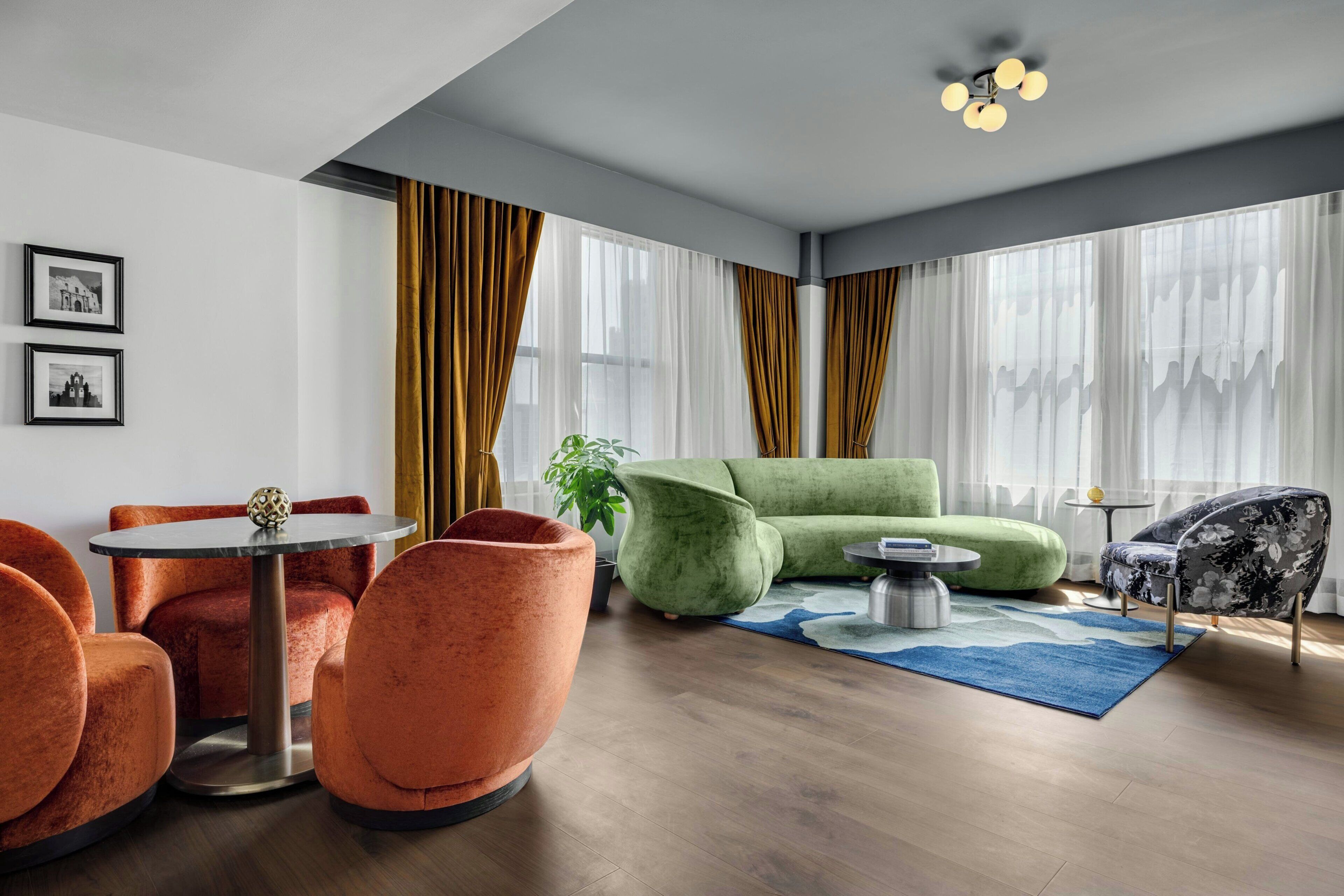 Uma sala de estar moderna com uma mesa redonda, cadeiras laranja, um sofá verde e um tapete azul.