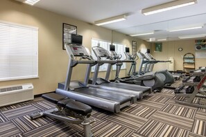 Een fitnessruimte met loopbanden, een stairmaster en krachtapparaten.