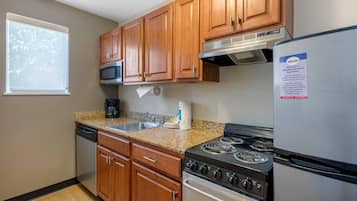 Una cocina con armarios de madera, un refrigerador de acero inoxidable, una estufa y un microondas.