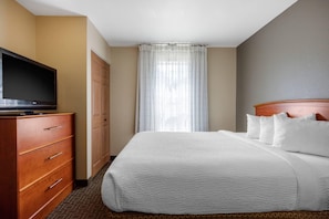 Una habitación de hotel con una cama, un televisor en una cómoda, un armario y una ventana con cortinas.