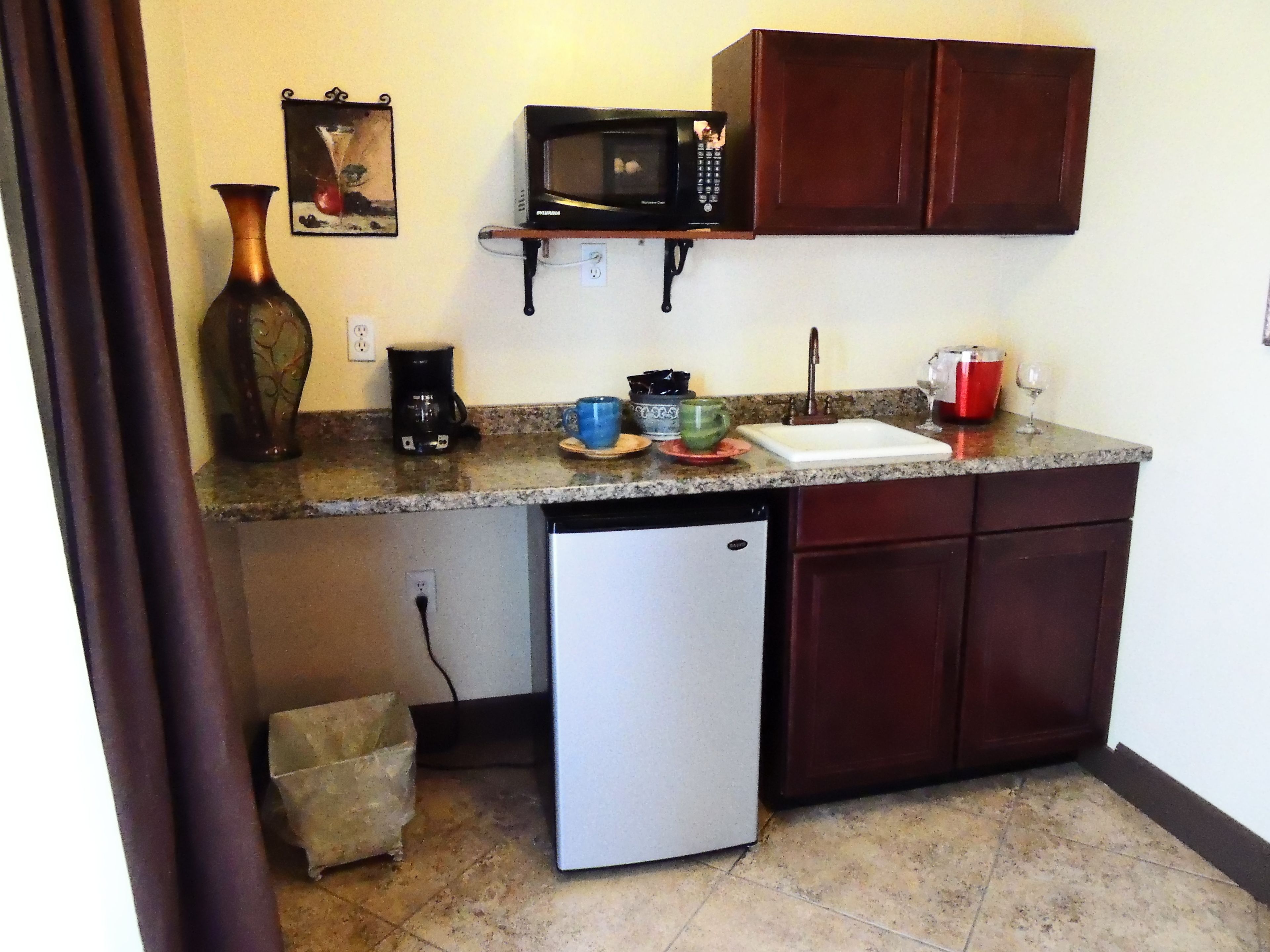 A compact kitchen with a refrigerator, microwave, and coffee maker.