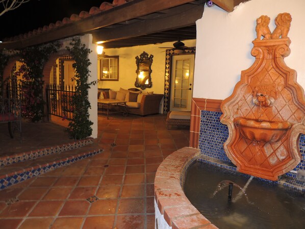 A courtyard with a fountain, tiled flooring, and a seating area with a sofa and table. - Tuscan Springs Hotel & Spa (Desert Hot Springs)
