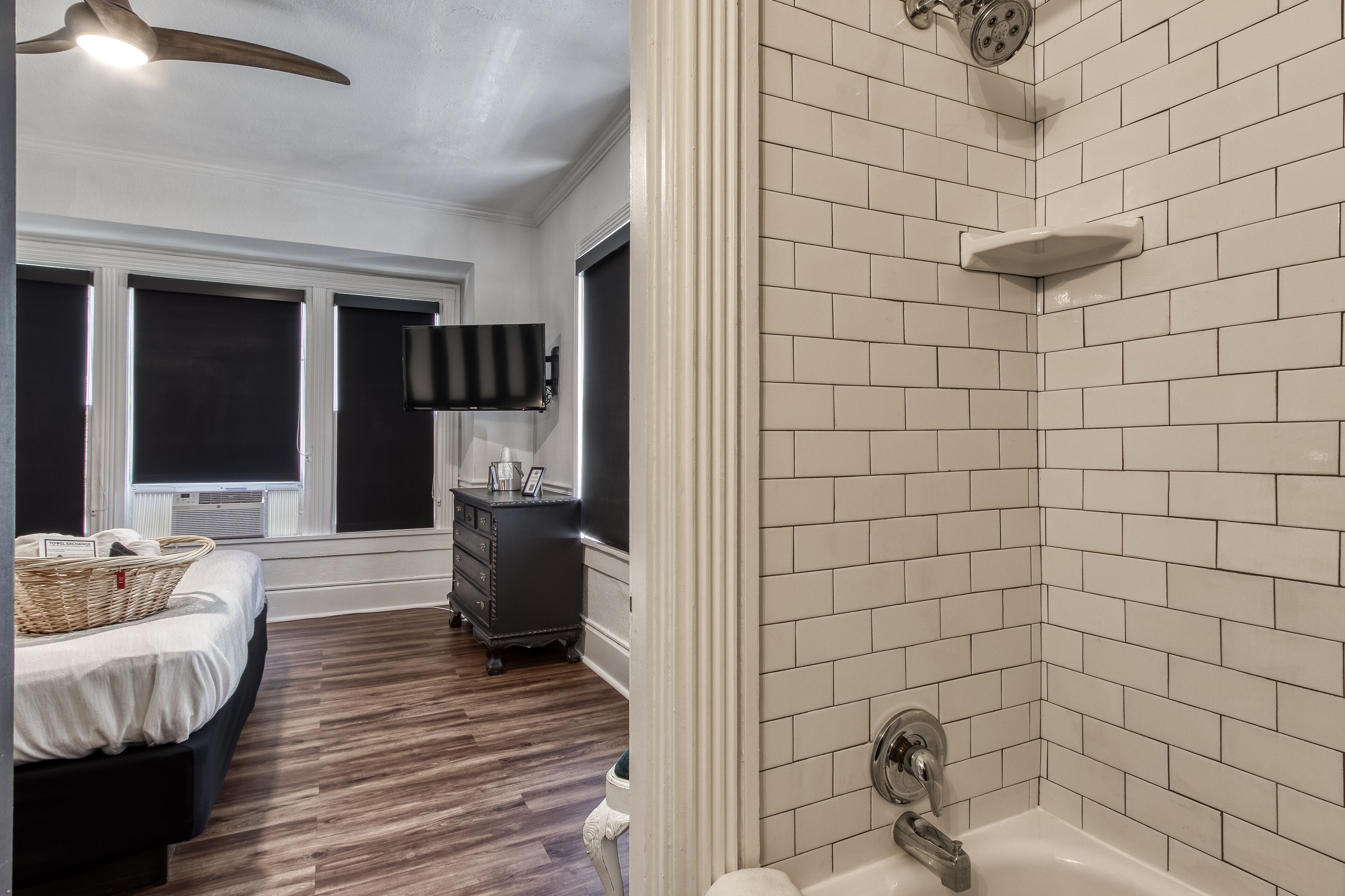 Une chambre à coucher avec un lit, une commode, un téléviseur et une fenêtre.
