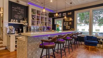 A bar area with a counter, stools, and shelves with bottles.