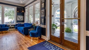 Un hall d’hôtel avec un plancher en bois, des canapés bleus et de grandes fenêtres.