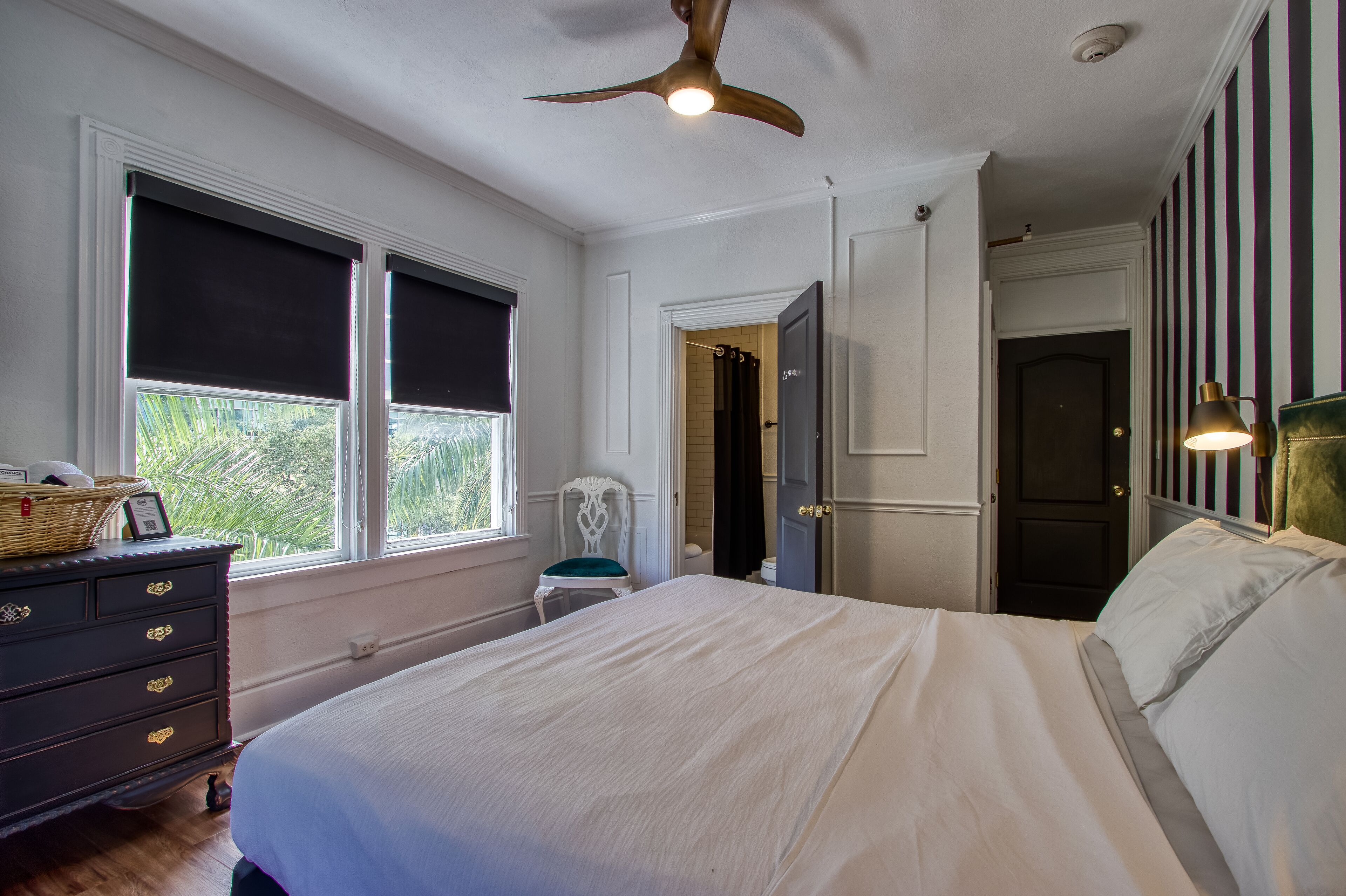 A bedroom with a bed, dresser, chair, and a ceiling fan.