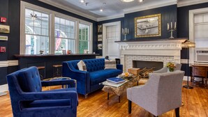 Un salon avec un canapé bleu, un fauteuil à motifs et une cheminée.