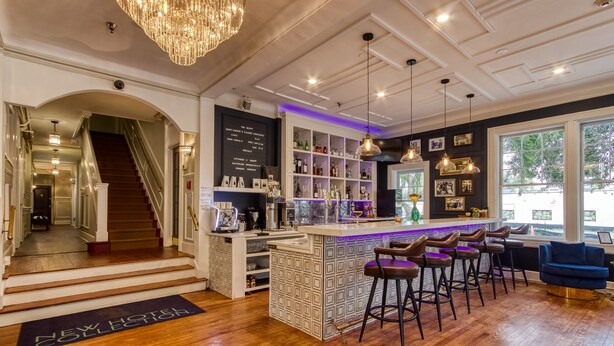 Un espace bar avec des tabourets, un comptoir et un escalier menant à un autre niveau.