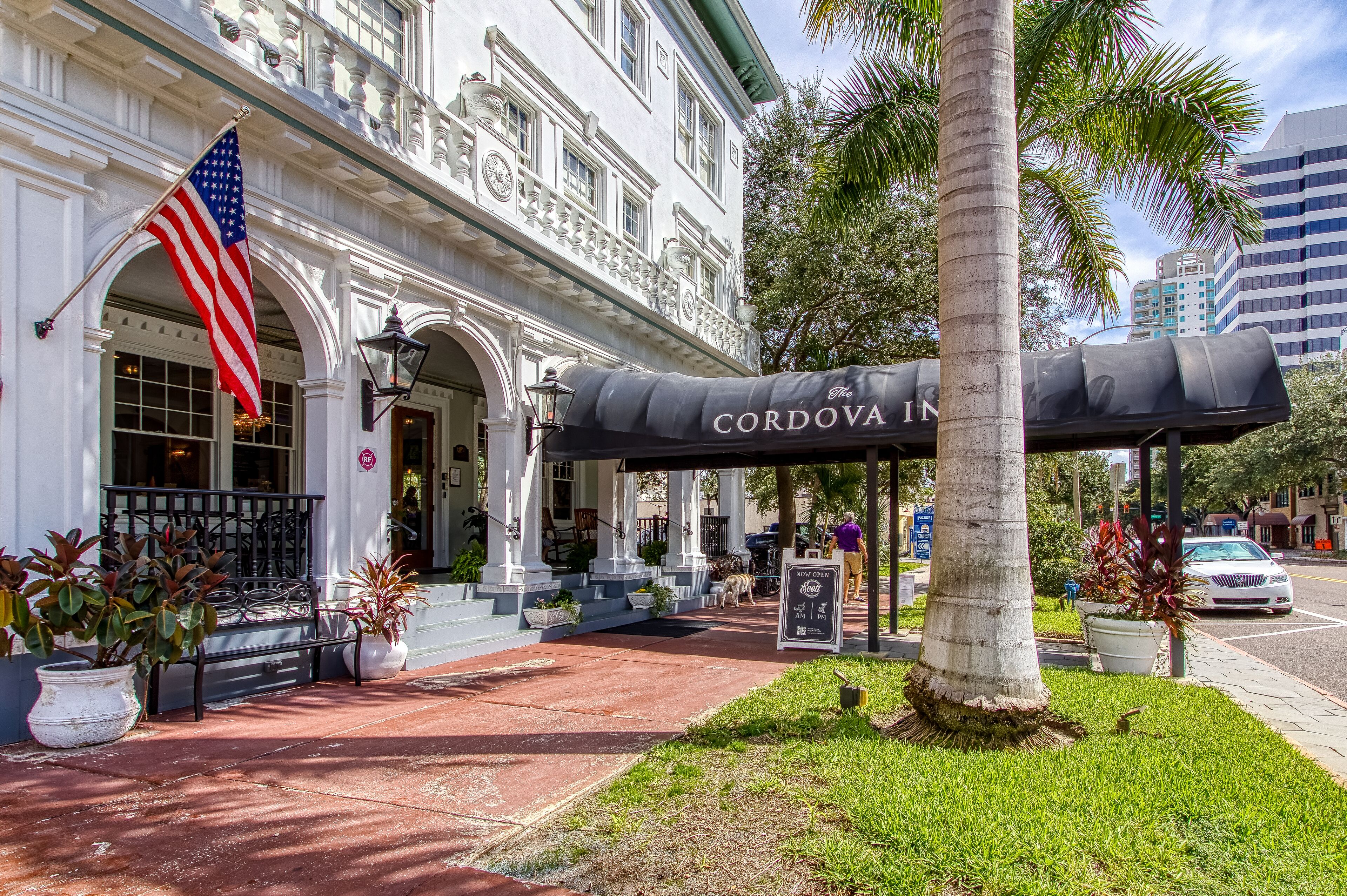 A historic building with an American flag, a covered outdoor seating area, and a sign for 'The Cordova Inn'.