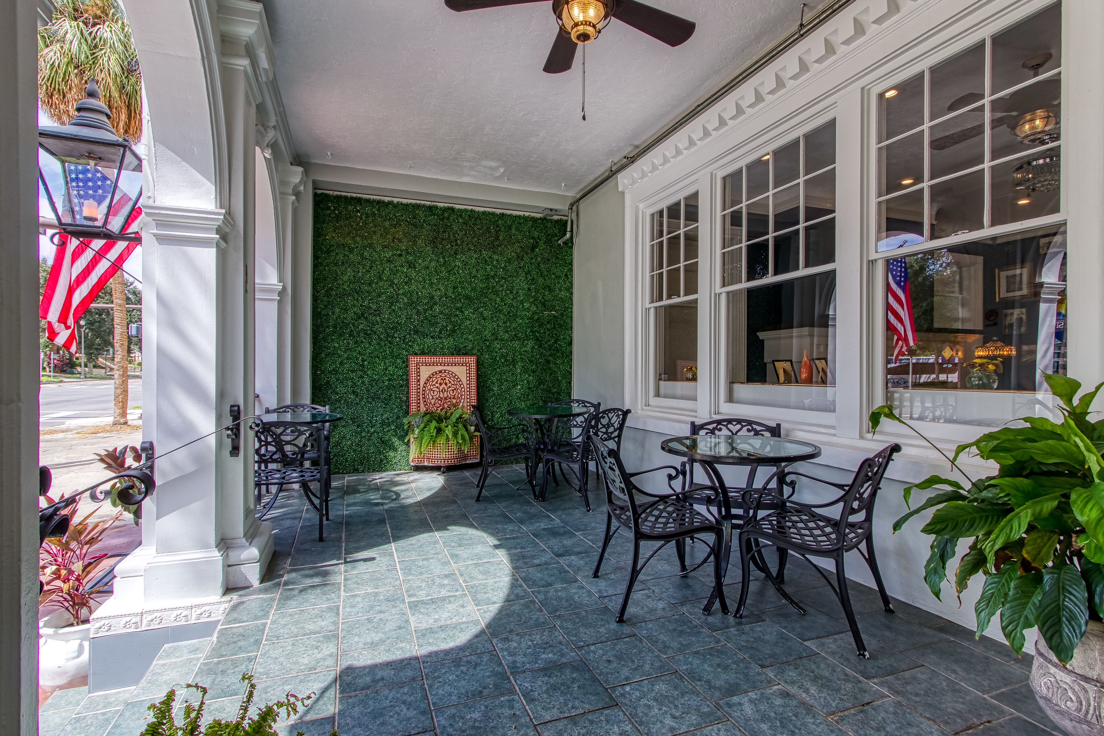 A covered patio with outdoor seating, a green wall, and an American flag.