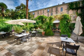 An outdoor patio with wooden flooring, tables, chairs, and umbrellas. - Villa Victoria (Nice)