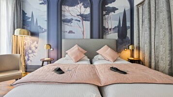 A double bed with two pillows, a bedside table with a lamp, a chair, and a large wall mural.