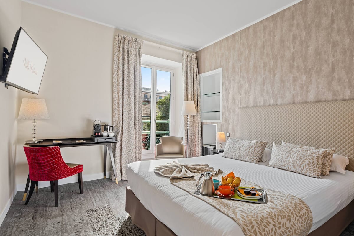 A hotel room with a bed, a desk, a chair, and a view of the outdoors.