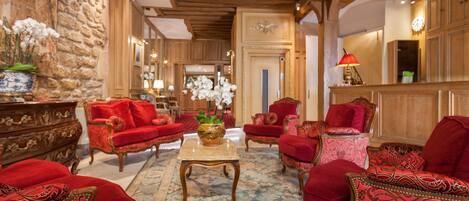 A spacious lobby with red upholstered furniture, a central coffee table, and a stone wall.