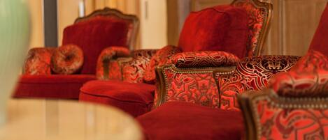 Una habitación con sillas tapizadas en rojo y una pequeña mesa redonda.