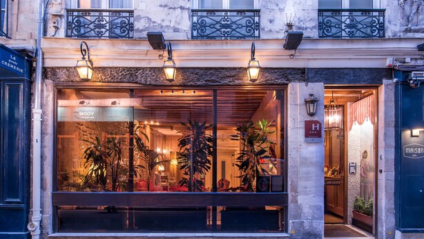 A hotel entrance with a large glass window, outdoor lighting, and a visible sign for "MOOY".