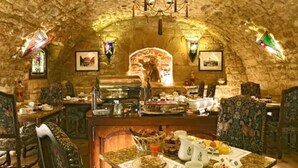 A stone-walled dining area with a buffet setup, including a variety of food items and a central serving station.