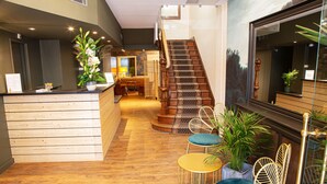 A reception area with a wooden counter, a staircase, and seating with chairs and tables. -  Hotelo Lyon Ainay (Lyon)
