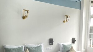 A hotel room with two beds, each with white bedding and green pillows. There are wall-mounted light fixtures and a window with curtains. -  Hotelo Lyon Ainay (Lyon)