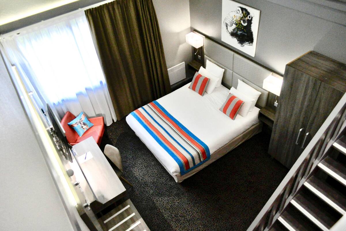 Une chambre d’hôtel équipée d’un lit, d’un bureau, d’une chaise, d’une armoire et d’une table de chevet avec une lampe.