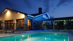 Ein Hotel mit Pool, Außenbereich und beleuchtetem Eingang.