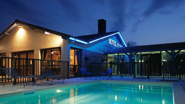 Ein Hotel mit Pool, Außenbereich und beleuchtetem Eingang.