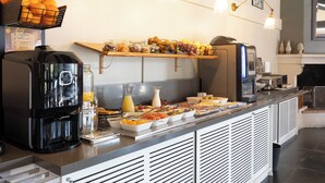 Ein reichhaltiges Buffet mit einer Kaffeemaschine, Obstschalen und einem Saftspender.