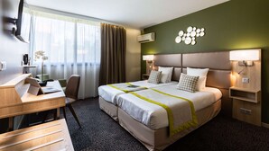Ein Hotelzimmer mit Bett, Schreibtisch, Stuhl und Fernseher.