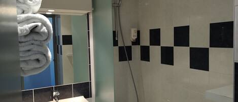 Un baño con lavabo, espejo y ducha.
