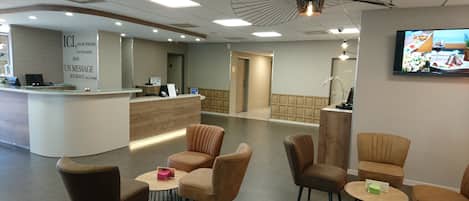 A reception area with a reception desk, several chairs, a television, and a patterned wall.