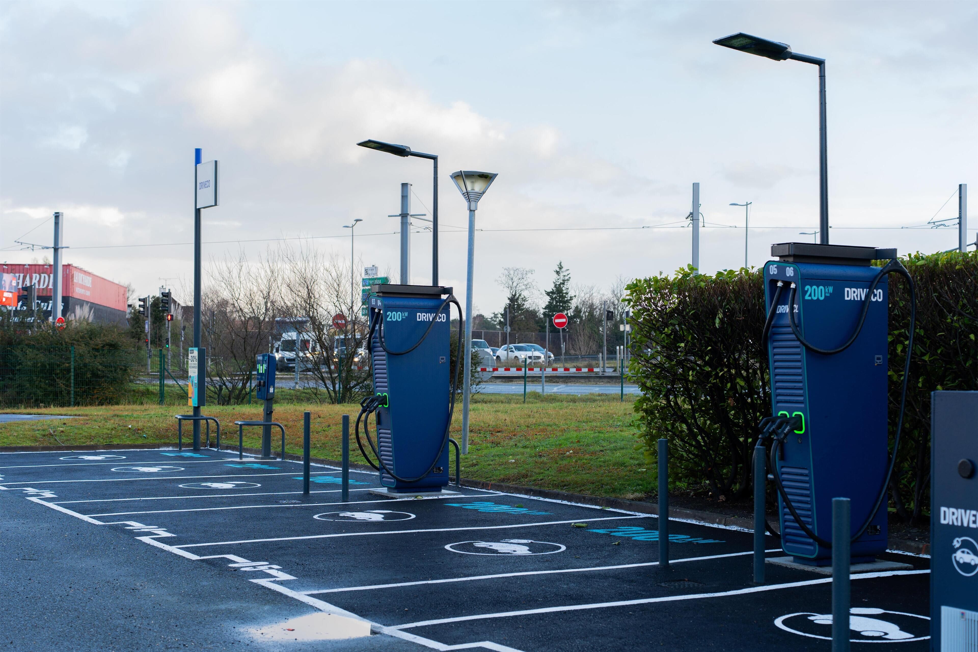 An electric vehicle charging station with a clear road layout and directional signs.