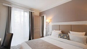 A hotel room with a large bed, a desk, and a chair. - Grand Hotel des Gobelins (Paris)