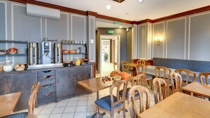 A restaurant with wooden tables and chairs, a coffee station, and a buffet area. - Grand Hotel des Gobelins (Paris)