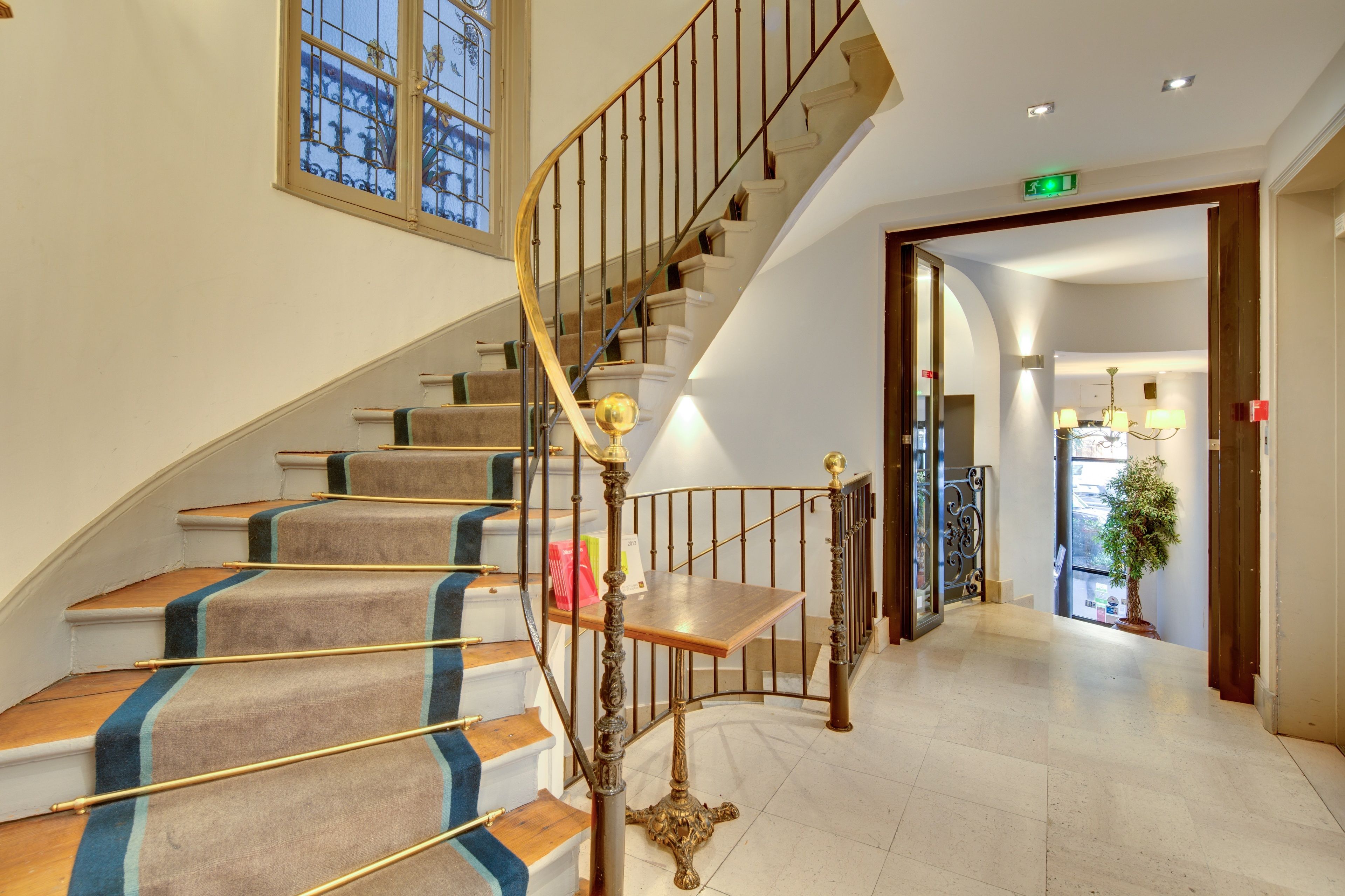 Eine prächtige Treppe mit geschwungenem Design, Teppichstufen und einem goldenen Geländer.