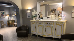 A room with a white and gold ornate cabinet, a black leather chair, and a patterned rug. - Hôtel Le Pré Catelan (Antibes)